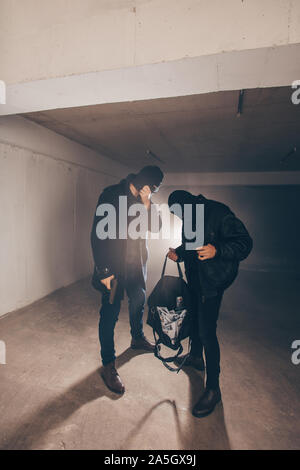 Masked men are holding guns and bag full of stolen money Stock Photo