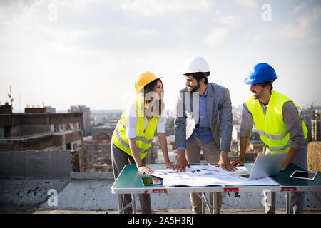 Architects team and engineers looking paper plans at construction site. Stock Photo