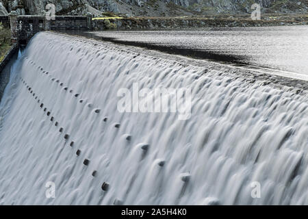 Caban Coch Dam in the Elan Valley Powys Mid Wales with water cascading over the lip after heavy rain. Stock Photo