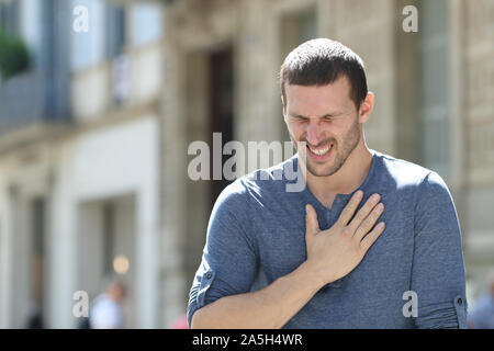 Stressed adult man complaining suffering chest ache standing in the street Stock Photo