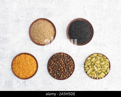 Spices and herbs set on concrete background in clay plate. Modern apothecary, naturopathy and ayurveda concept. Stock Photo