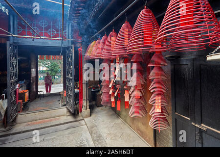 Burning incense spirals hanging on rails in Tin Hau Temple Complex. Yau Ma Tei, Kowloon, Hong Kong. Stock Photo