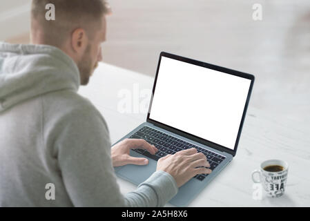 Guy work on laptop with isolated screen for mockup. Clean work desk with cup of coffee beside. Stock Photo