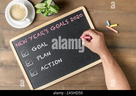 Hand man writing New year goals 2020 text on black board. Business motivation and inspiration concepts Stock Photo