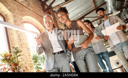 Business experts. Two colleagues discussing new project while walking through the office corridor Stock Photo