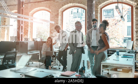Working together. Group of modern people communicating and discussing fresh ideas while standing in the creative office Stock Photo