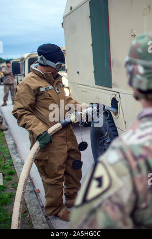 17 October 2019, Saxony-Anhalt, Burg: A soldier of the US army refuels a military vehicle of a US brigade from Fort Hood in Texas in the Clausewitz barracks at an improvised gas station. The force is currently crossing Germany and is on its way to Poland to participate in Operation Atlantic Resolve. The objective of the operation is to ensure the operational readiness of NATO troops. 'Atlantic Resolve' had been decided in response to the Russian annexation of the Crimea. In the Clausewitz barracks in Burg, the approximately 440 soldiers with around 220 wheeled vehicles will gradually rest and Stock Photo