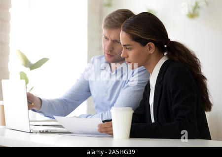 Middle aged male manager showing software to concentrated female colleague. Stock Photo