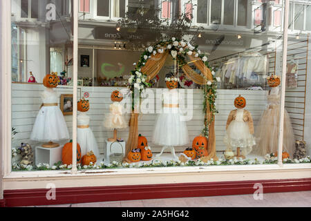 Halloween pumpkins used as heads upon white dresses in a creative boutique shop window display. Stock Photo