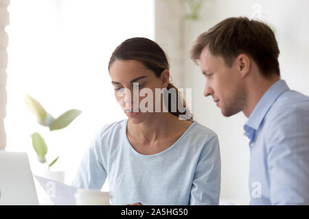 Millennial mixed race concentrated female employee working with colleague. Stock Photo