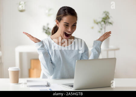 Surprised young mixed race businesswoman received email with good news. Stock Photo
