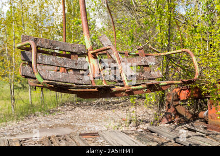 Old broken rusty metal radioactive children's electric wheel abandoned, the park of culture and recreation in the city of Pripyat, the Chernobyl disas Stock Photo