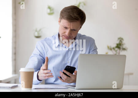 Stressed young man irritated by bad mobile phone work. Stock Photo