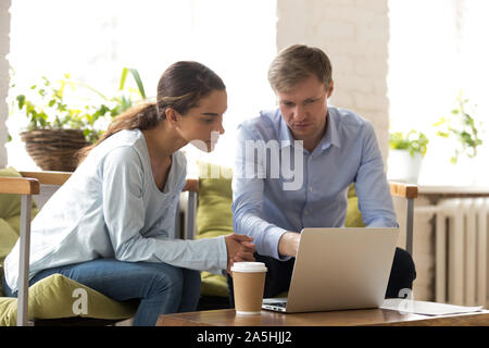 Concentrated multiracial coworkers looking at laptop screen, busy with project. Stock Photo