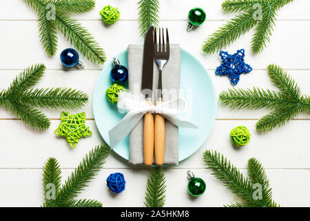 Top view of New Year dinner on festive wooden background. Composition of plate, fork, knife, fir tree and decorations. Merry Christmas concept. Stock Photo