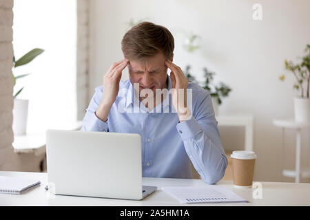 Exhausted middle aged businessman suffering from strong head ache. Stock Photo