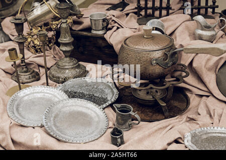 Brass containers and plates, candle holders  and other old vintage copper cookware in the flea market. Still life toned image. Stock Photo