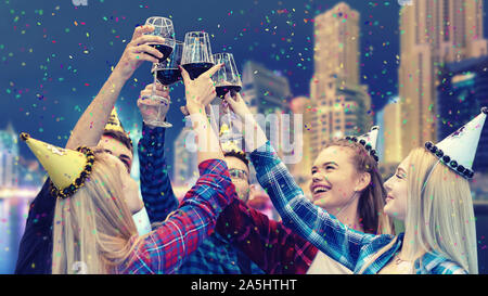 Young people having fun drinking red wine at night party on rooftop Stock Photo