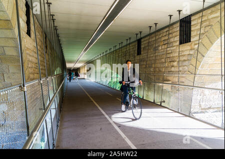 A female cyclist on the cycle path suspended under Pont Adolphe, Adolphe Bridge, Luxembourg city, Grand Duchy of Luxembourg Stock Photo