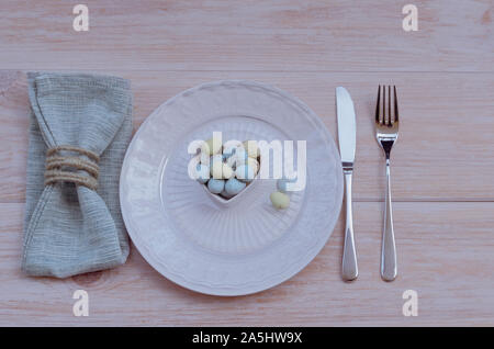 Happy Easter concept. Top view of beautiful spring table settings in pastel tone, blue linen napkin with rustic napkin ring  and bowl with chocolate E Stock Photo
