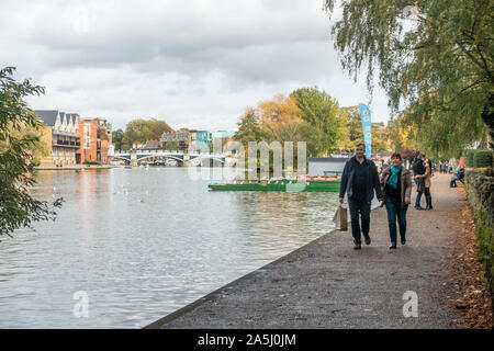 People walk along a riverside path alongside The River Thames at Windsor in Berkshire, UK Stock Photo