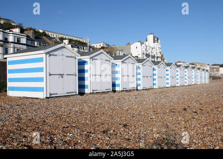 A row of blue and white striped beach huts on a stony Hastings beach, 2019 in October Stock Photo