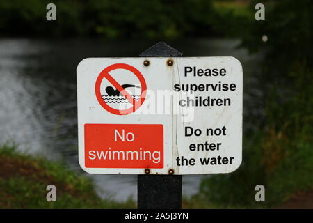 A no swimming sign beside a river Stock Photo