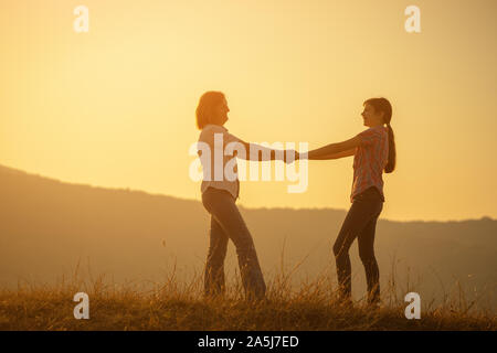 Happy family enjoying sunset. Grandmother and granddaughter holding hands. Stock Photo