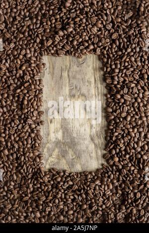 Vertical shot of a coffee beans frame over a wooden surface great for background or writing text Stock Photo