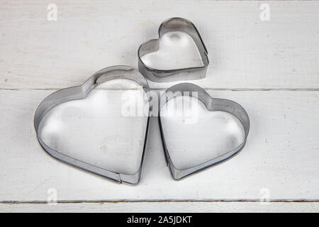Forms for cookies in the shape of a heart on a wooden table. Stock Photo
