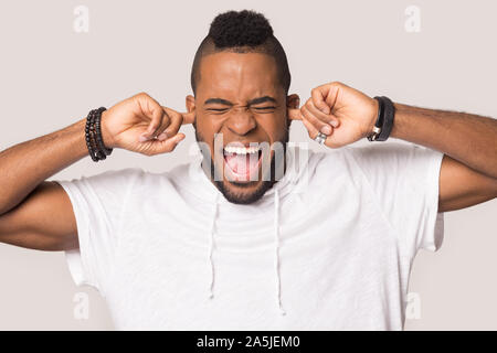 Mad african American man plug ears avoiding noise Stock Photo