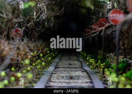 Blurred scary dark thigh background. Scenery for Halloween. The railway goes into the dark, dry tree branches and a stop sign. Stock Photo