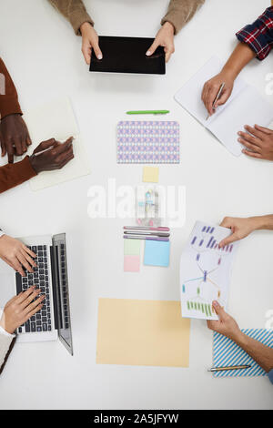 Top view of unrecognizable young people sitting at table and discussing group project with hands holding graphs and charts, copy space Stock Photo