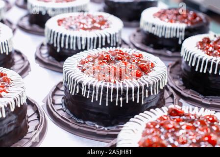 Many beautiful and delicious chocolate cakes with fresh cherry and cream. Confectionery production for the manufacture of cakes and pastries, torte, c Stock Photo