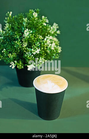 Cup of cappuccino and green plant on mint background Stock Photo