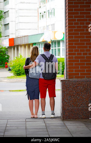 Back view of beautiful couple hugging and looking outdoors.