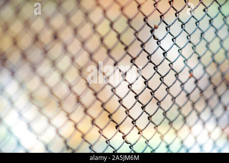 Old rusty mesh fence. Blurred colorful background. Stock Photo
