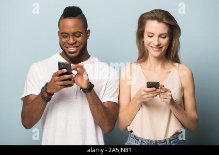 Smiling multiracial couple using modern smartphones internet connection Stock Photo