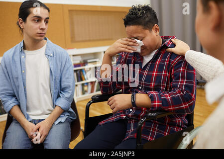Portrait of disabled Latin-American woman crying sitting in wheelchair during support group meeting, copy space Stock Photo