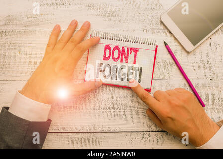 Text sign showing Don T Forget. Business photo text used to remind someone about important fact or detail Hand hold note paper near writing equipment Stock Photo