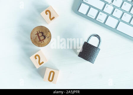 Bitcoin with numbers 2020 on cubes on a white wooden background with a keyboard and a lock. Cryptocurrency security concept in the new year. Flat lay, Stock Photo