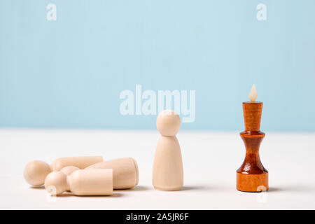The concept of dismissal of employees. The figure of the wooden king on a blue background looks at the figures. Close up. Stock Photo