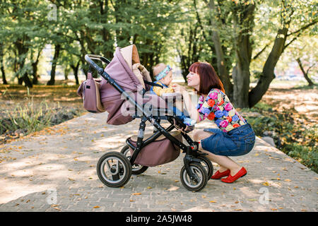 Young mother looking at her child in a baby stroller Stock Photo