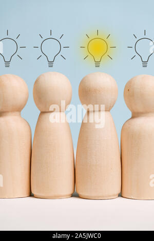 Wooden figures standing in a row with light bulbs above them. Concept of birth ideas. Close up. Vertical. Stock Photo