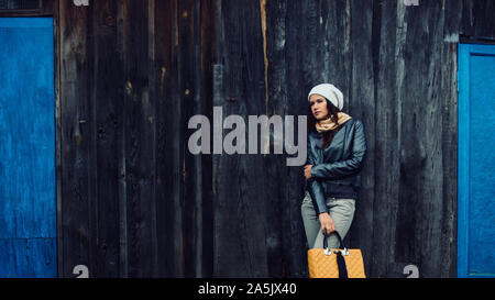 frustrated young woman standing near an old wooden house. Stock Photo