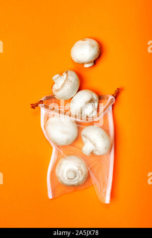 Cute organic champignons in the eco bag on a trendy orange background. Zero waste concept, plastic-free, eco-friendly shopping, vegan Stock Photo