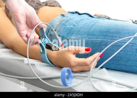 The doctor attaches the electrodes of the ECG pegs to the patients wrist. Stock Photo