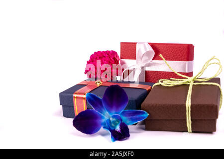Three gift boxes with beautiful ribbons and threads, blue orchid flowers and pink carnation on white background for copy space Stock Photo
