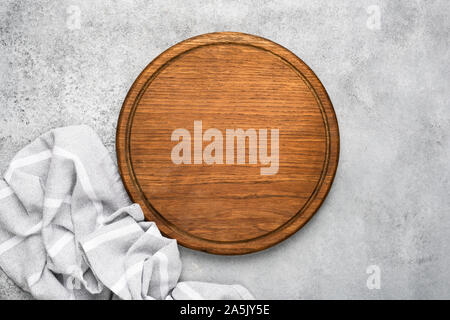 Round wooden cutting board and linen textile on grey concrete background with copy space for text. Food background Stock Photo