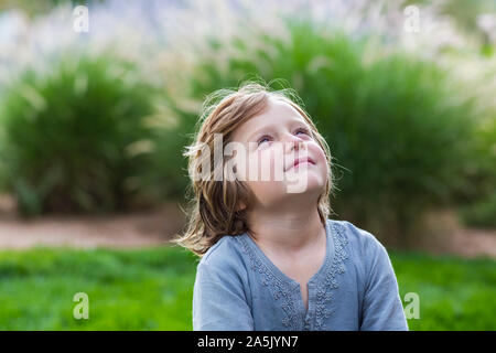 5 year old boy relaxing on lush green lawn looking up Stock Photo